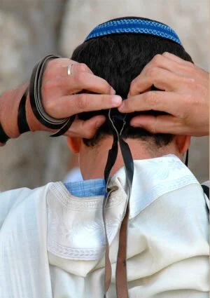Rear view of man fixing head tefillin at the Western Wall in Jerusalem
