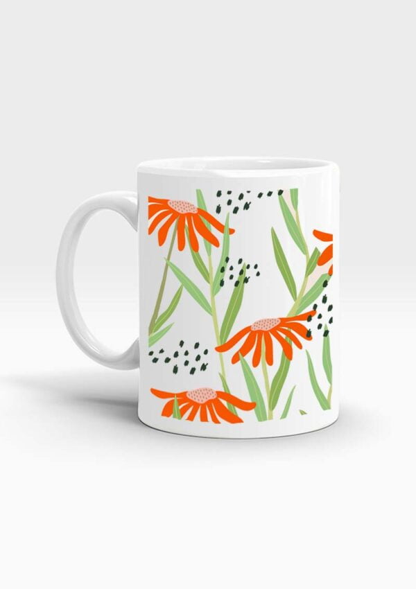 White mug decorated with illustration of bright orange flower petals, green leaves, and abstract black dots